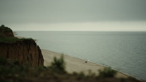 Calm-landscape-sandy-seashore-with-green-hills.-Ocean-waves-washing-coastline.