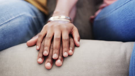 close up of hands of african american couple holding hands sitting on couch at home, in slow motion