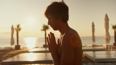 close-up shot of a guy meditating on a sunny beach in the morning