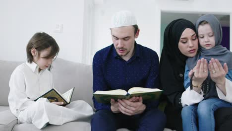 muslim family reading quran and praying together on the sofa