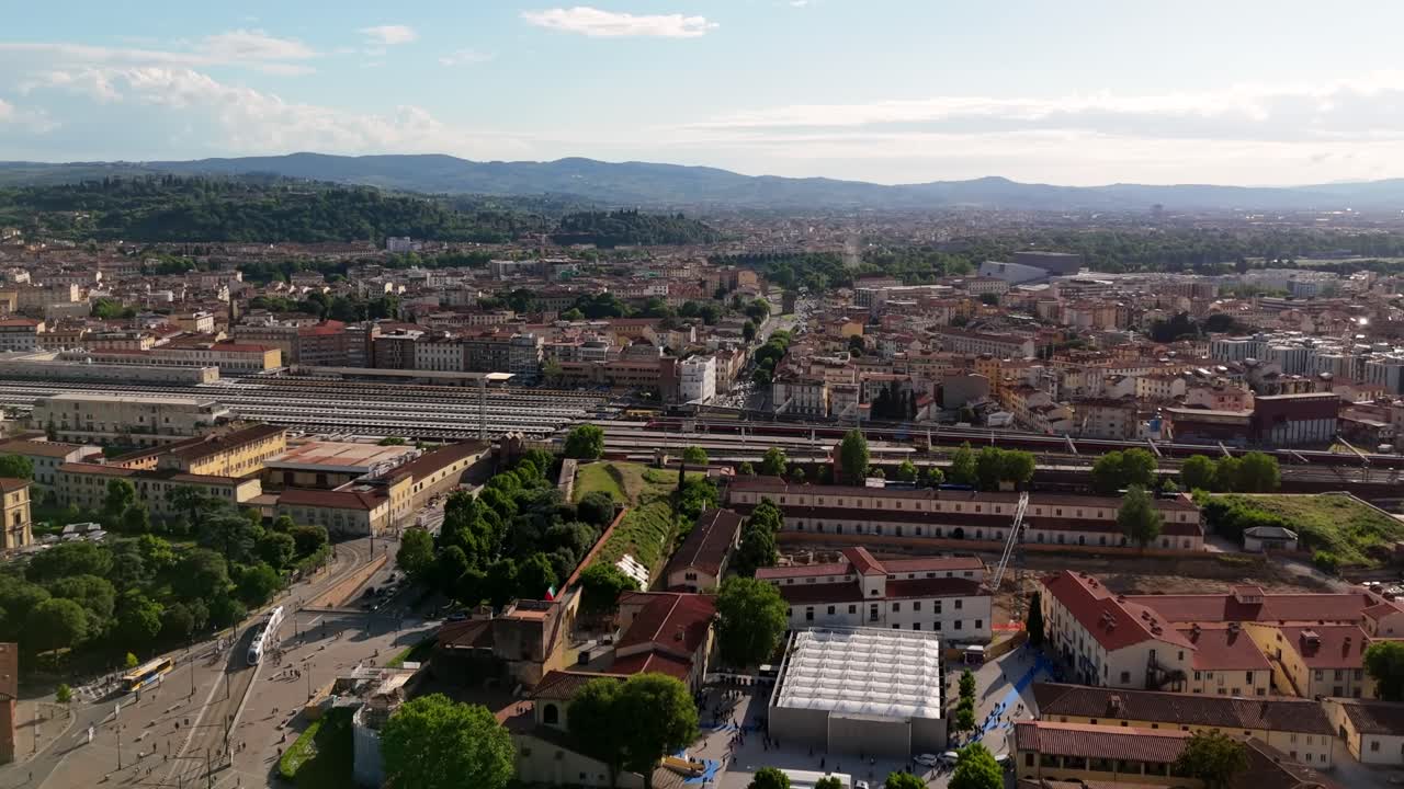 Firenze, Italia, con le montagne sullo sfondo e un treno che attraversa l'idilliaca città europea - ripresa aerea con avanzamento.