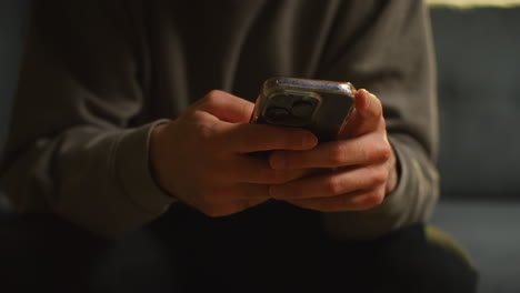 close up of man spending evening at home sitting on sofa wearing wireless headphones streaming music or watching content from mobile phone 1