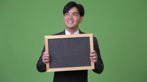 젊은 잘생긴 아시아 사업가 블랙보드를 보여줍니다.