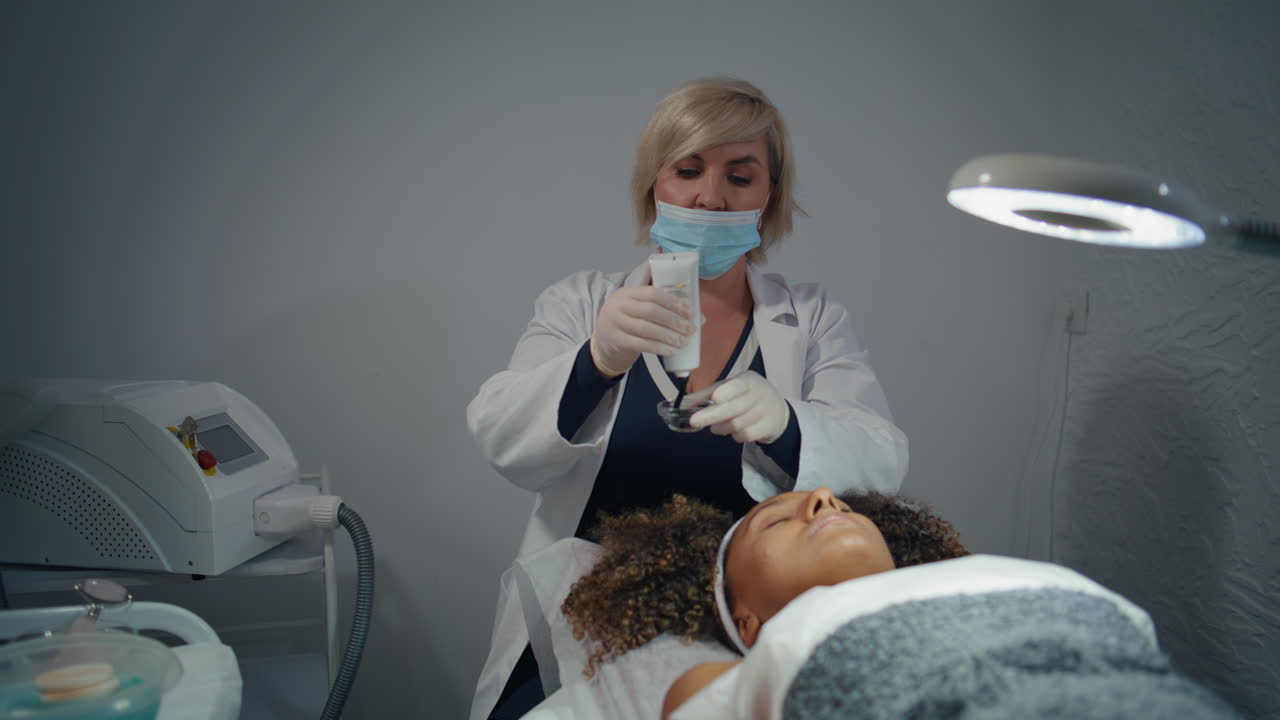 cosmetólogo apretando la máscara facial en el frasco. cliente visita al dermatólogo