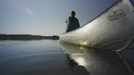 woman canoeing on a calm lake at sunset