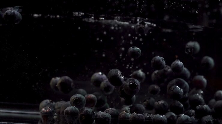Mirtilli che galleggiano liberamente nell'acqua su sfondo nero