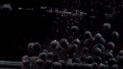 Blueberries-Floating-free-In-Water-Against-Black-Background