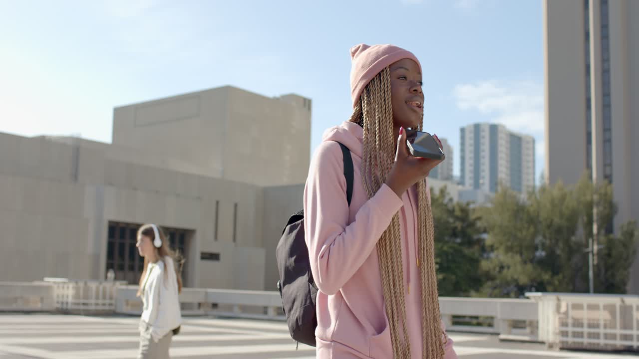 Studentessa afroamericana che inizia una telefonata parlando al telefono in una piazza del campus