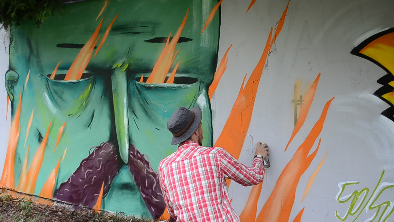 L'artista disegna graffiti su una recinzione.