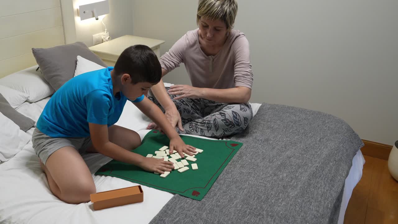 Family playing dominoes on the bed