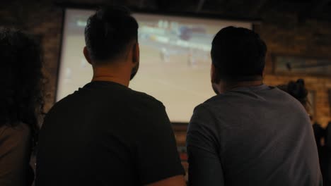 group of friends cheering to soccer match in the pub.