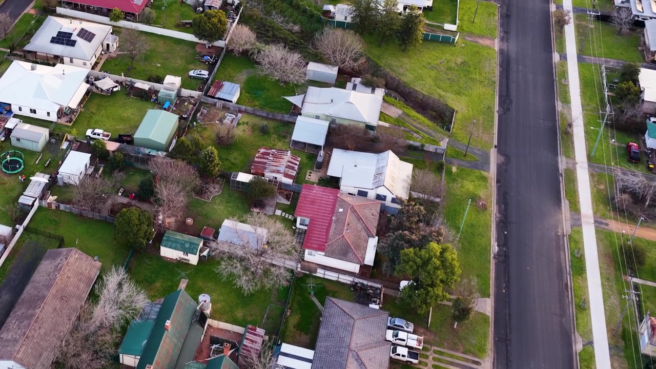 Ripresa aerea con drone sopra i tetti suburbani, i giardini sul retro e le tranquille strade residenziali a Coonabarabran, Australia