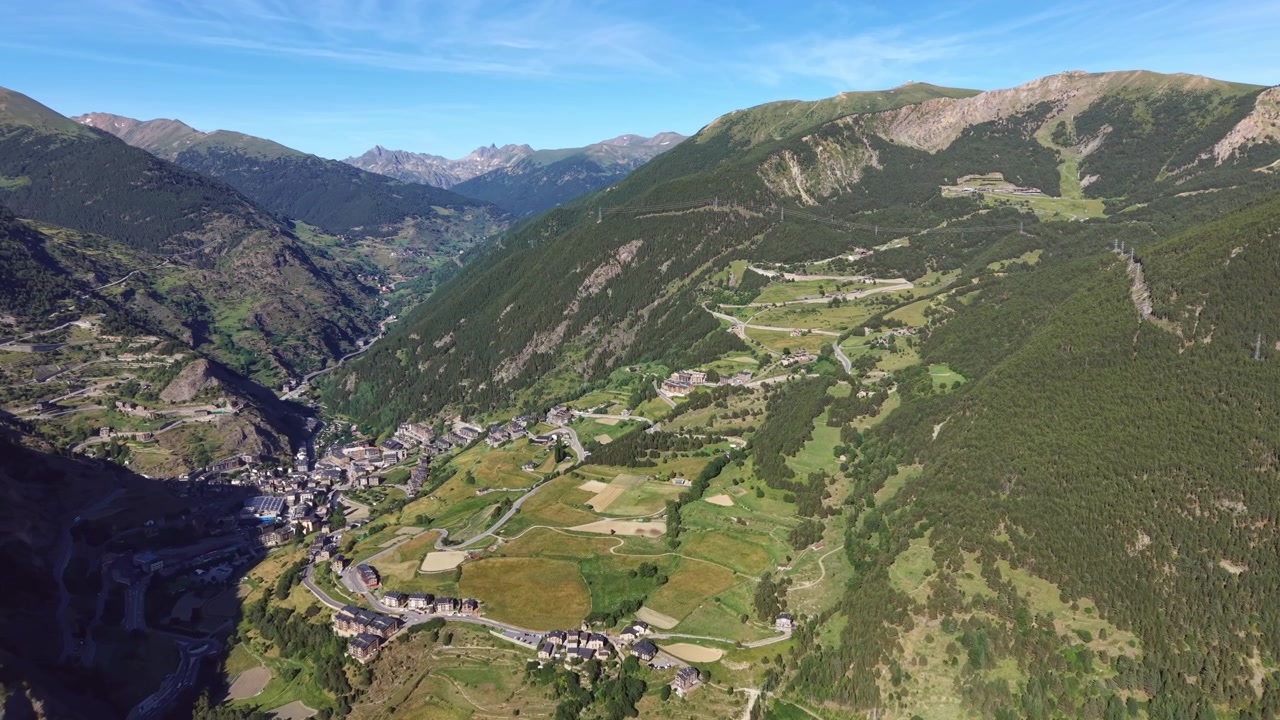 Villaggio di Canillo incastonato in una verde valle pirenaica in Andorra, circondato da pendii montuosi boscosi, terrazzamenti agricoli e strade tortuose sotto un cielo azzurro limpido