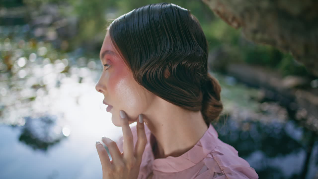 우아한 여성은 이 많은 숲에서 호수의 아름다움을 즐기고 있습니다. 연못에서 포즈를 취하는 모델