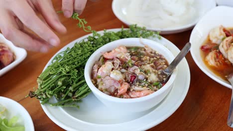 hands garnishing a bowl of asian cuisine