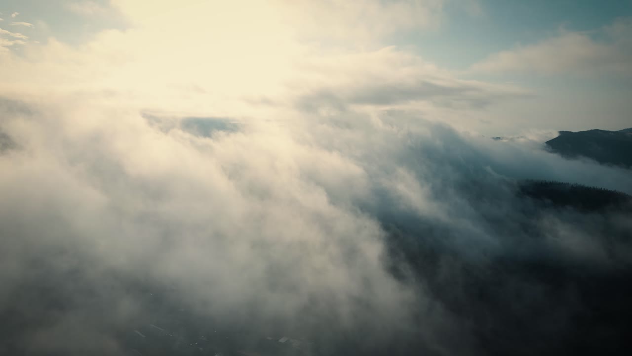 Aerial flying backwards among clouds illuminated by suns rays