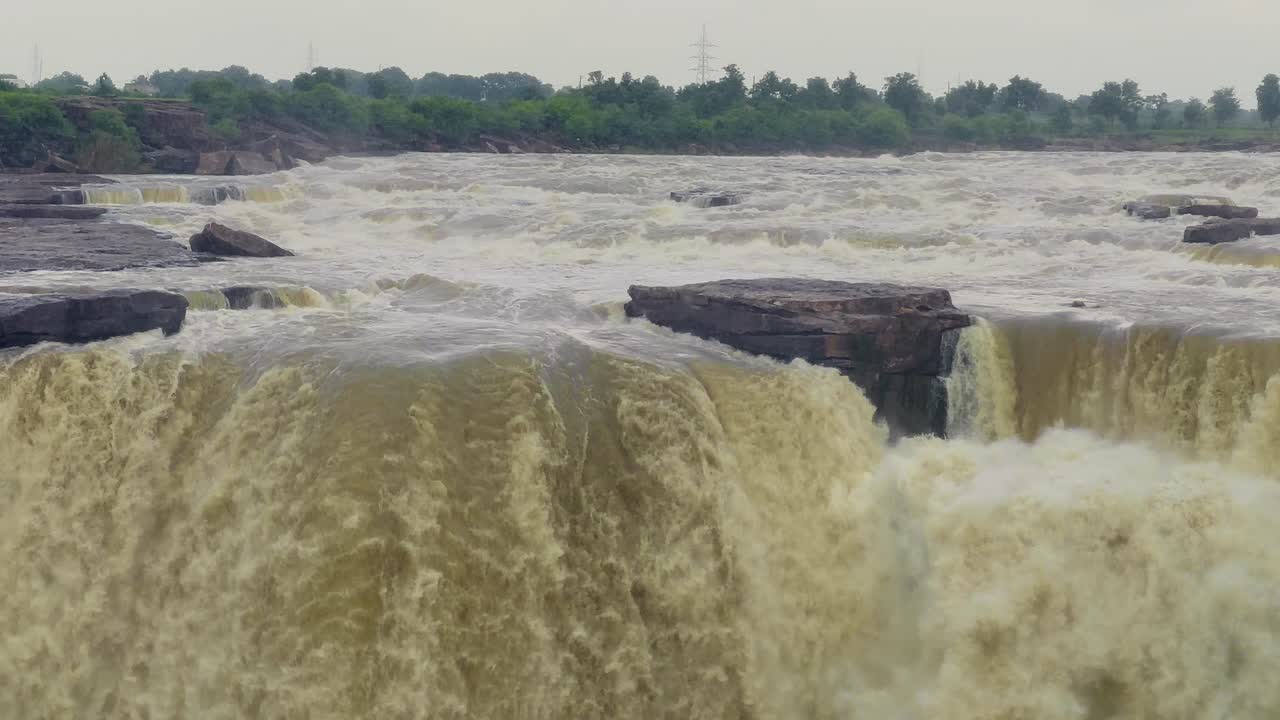 closeup of captivating shot of waterfall in the rainy season, surrounded by lush vegetation and set against a dramatic cloudy sky