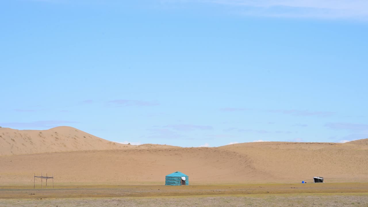 A rare blue ger, a traditional nomadic dwelling, stands alone in the remote Durgun Nuur desert, Mongolia. This wide shot captures the unique home against a backdrop of vast sand dunes