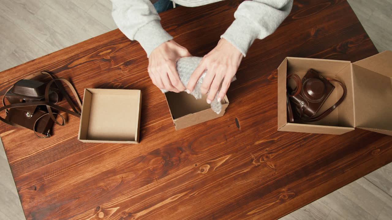 Person Carefully Packing Vintage Camera in Bubble Wrap for Shipping