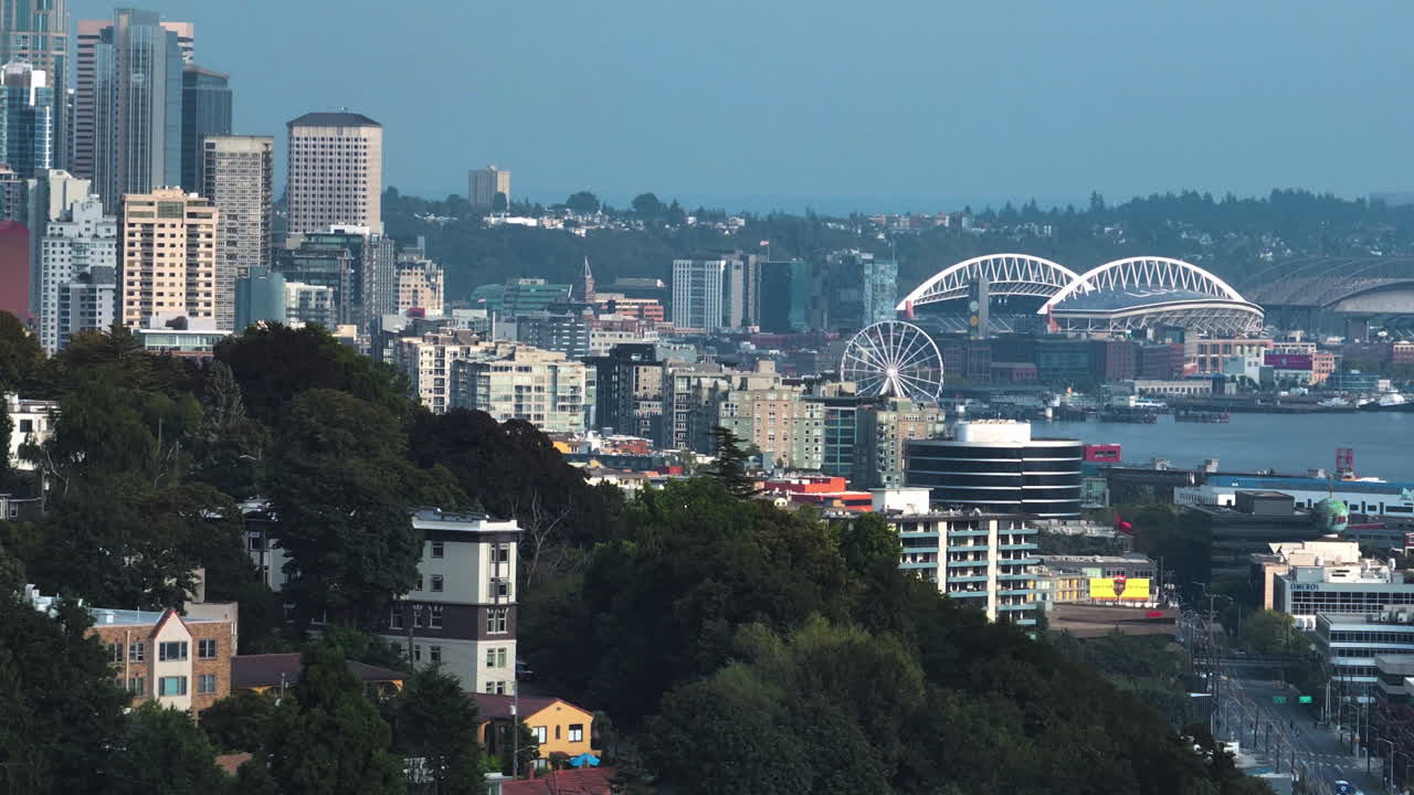 Telephoto drone shot behind hills, revealing the skyline of Seattle, sunny day