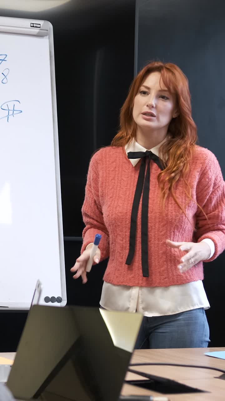 Businesswoman explaining strategy on whiteboard to diverse colleagues in conference room