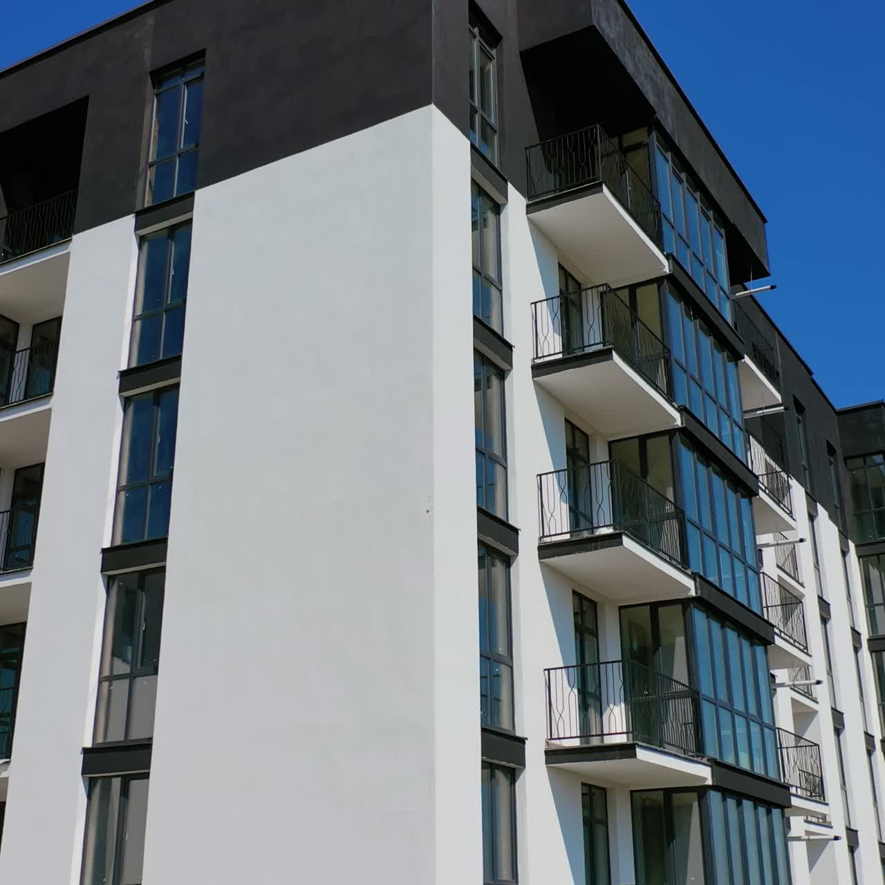 Newly built modern apartment building facade. Exterior of multi storey building. Modern design of urban architecture. Aerial view. Motion up.