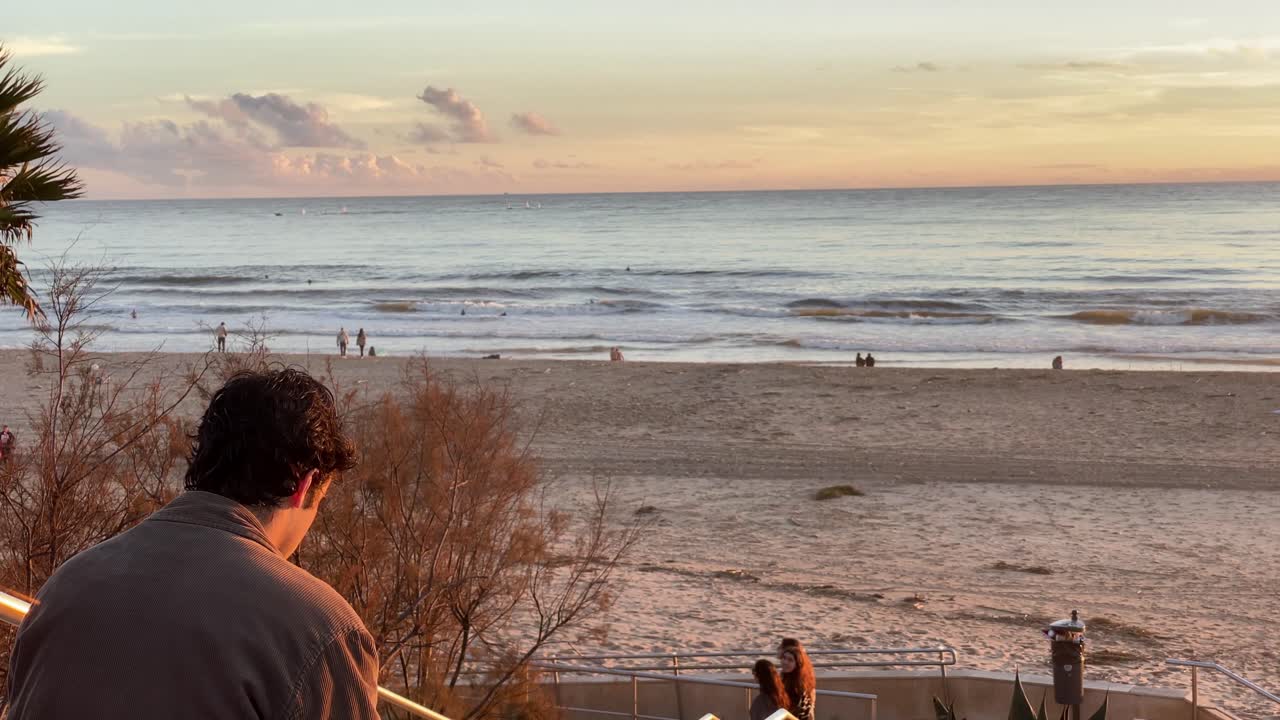 담배를 피우며 일몰을 배경으로 바다를 배경으로 해변을 생각하는 남자의 실루엣
