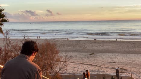 silhouette of a man smoking a cigarette and thinking over beach at sunset with ocean in background