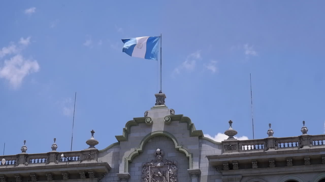 Guatemalas flag vajer på en blå himmel over paladset i Guatemala City.