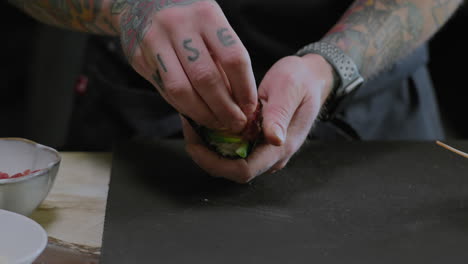 closeup shot of a chef preparing sushi hand rolls