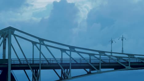 time lapse of beautiful fast moving dark gray rain clouds over the oskara kalpaka swing bridge in liepaja city in evening, medium shot shot