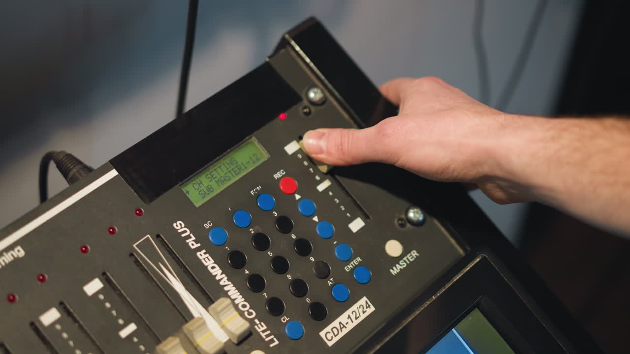 Close-up shot of hand adjusting dial on professional video equipment. Setting controls on multimedia device, focusing on buttons with LED display in studio lighting, cinematic effect in action