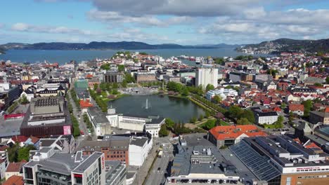 forward moving aerial bergen city centre with water fountain in park and seafront in the background - norway