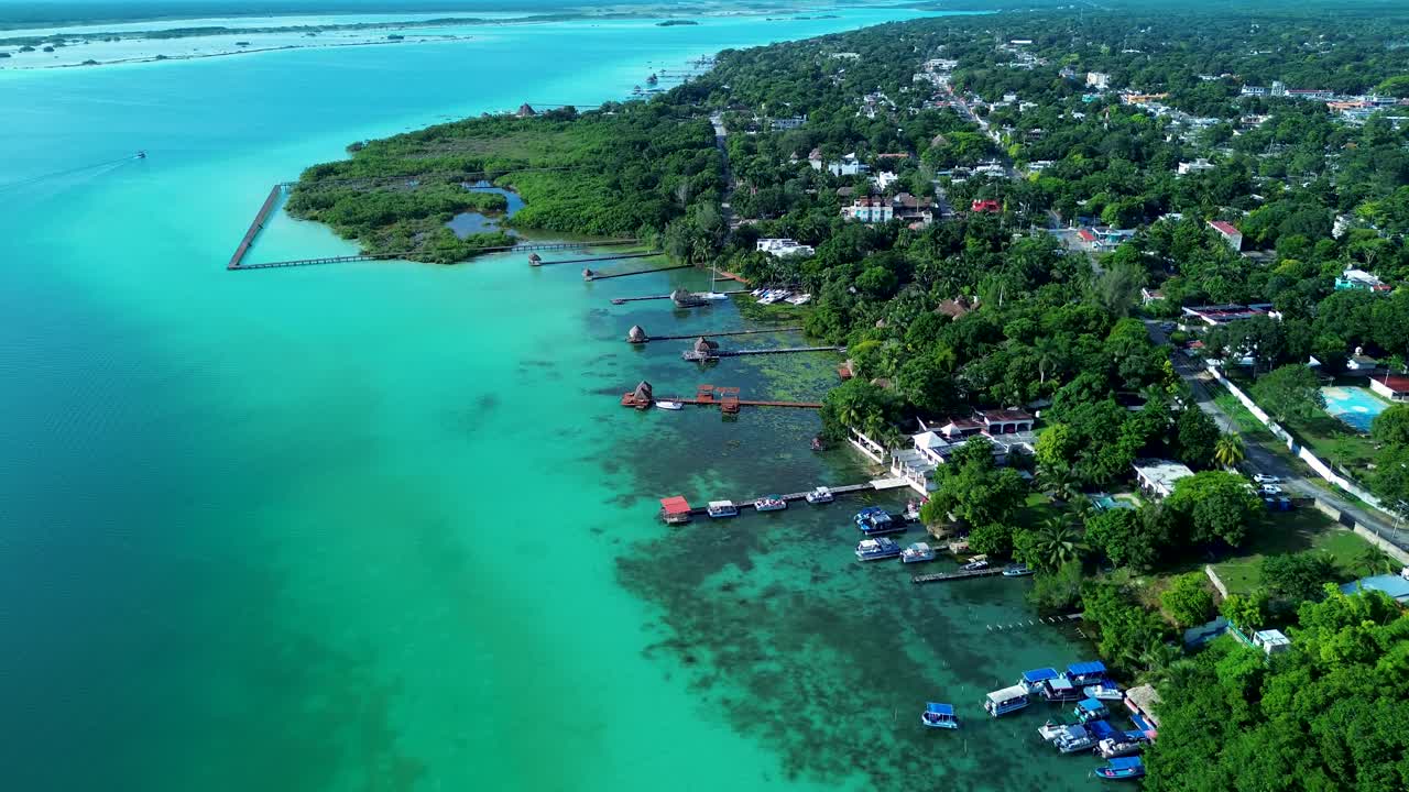 Drone aerial landscape of Bacalar village town suburbs with huts resorts hotels and jetty boardwalk wharf in clear lake lagoon Mexico boating vacation holidays rainforest