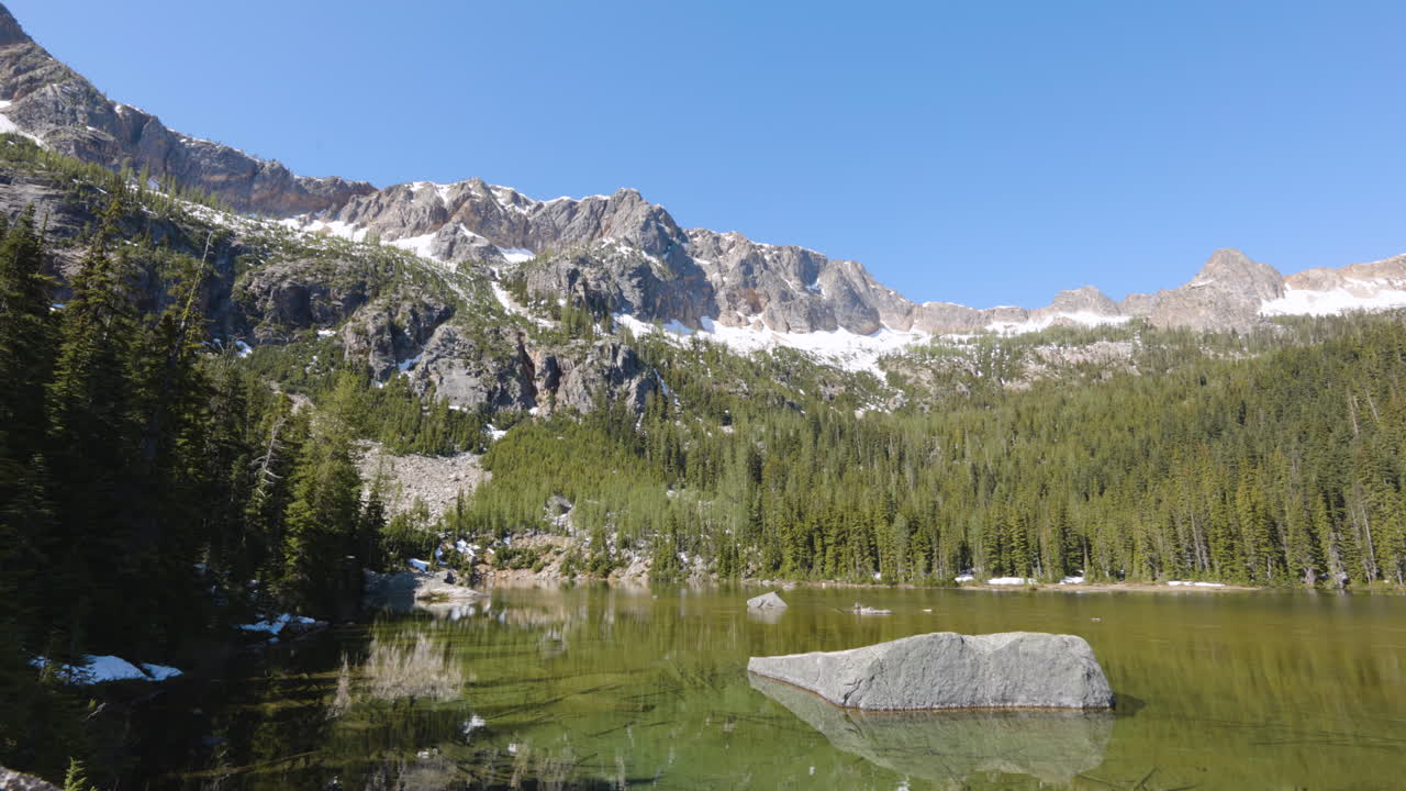 alto pico de montaña por encima de un lago alpino con vastos bosques
