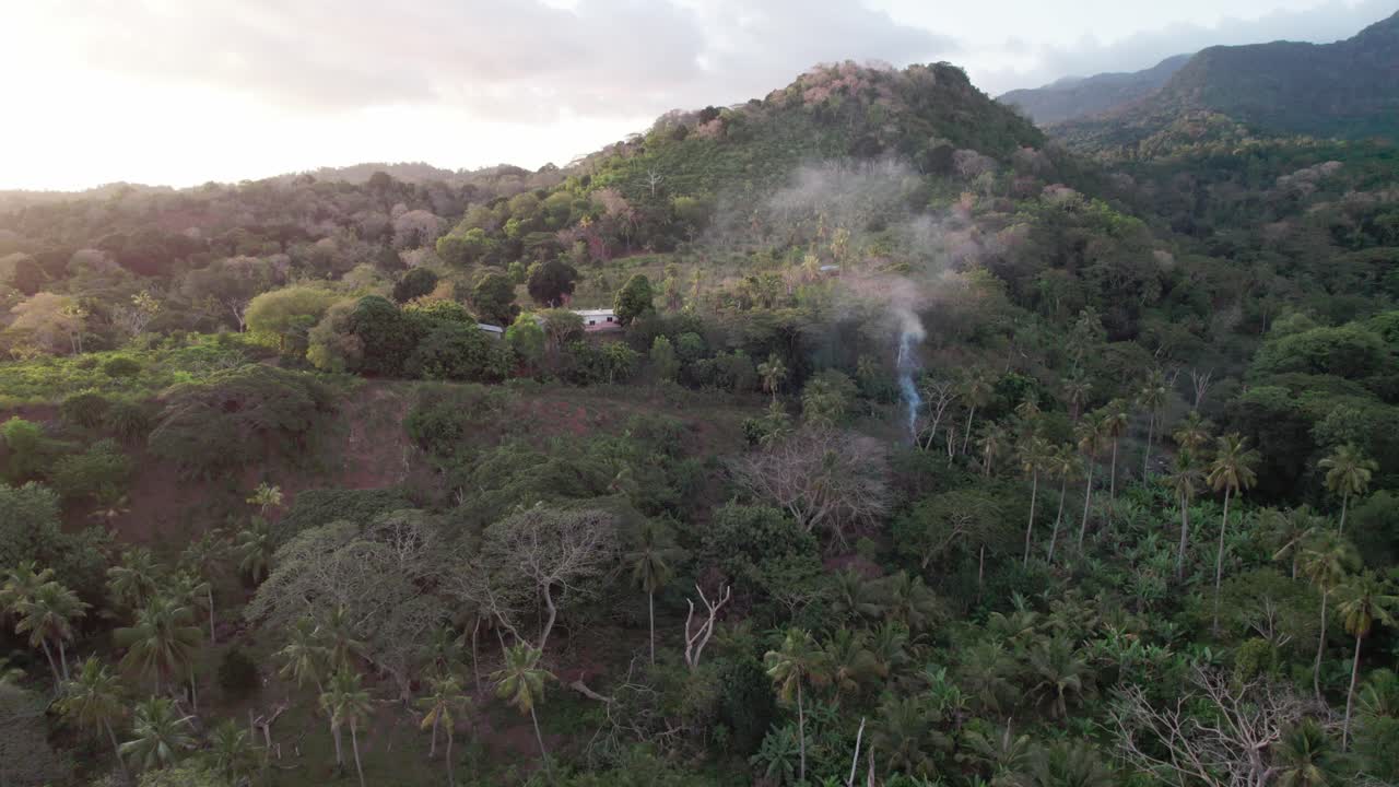 penacho de humo en medio de la selva tropical, con montañas en segundo plano.