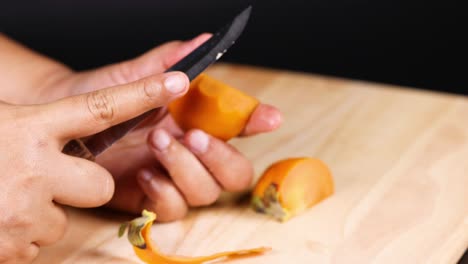 hands skillfully peeling a ripe persimmon