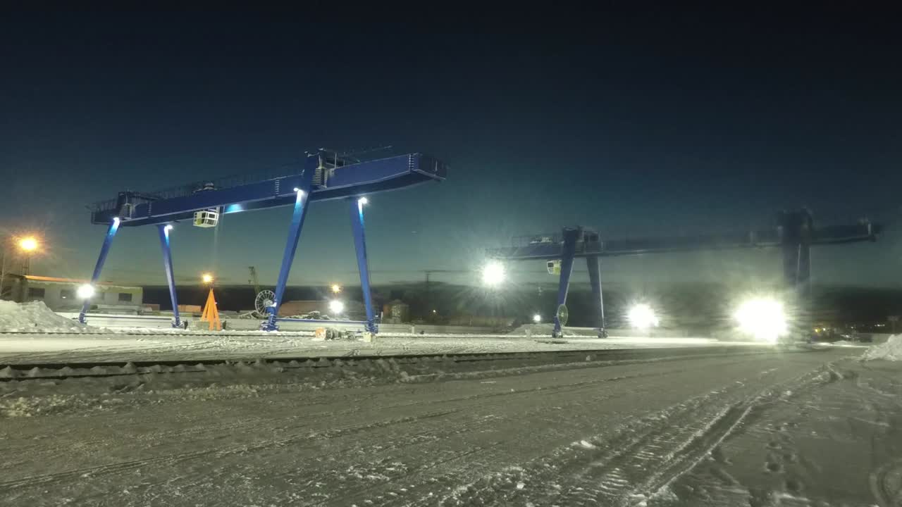 Nighttime Industrial Gantry Crane Operation in a Snowy Environment