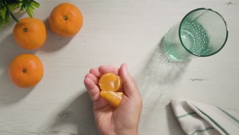 Top-shot-view-hand-throw-Mandarin-slices-in-the-air,-white-table-background---Slow-motion