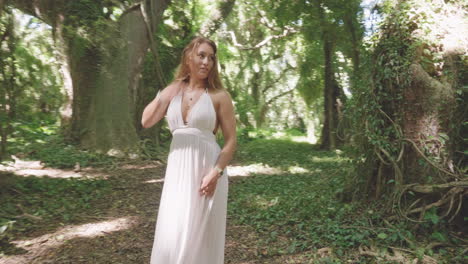 woman in boho white dress surrounded by tropical jungle in sunlight