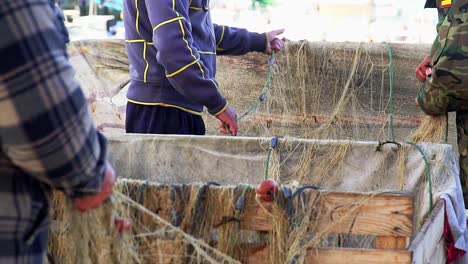 Close-up-of-unrecognizable-fishermen-in-port-collecting-fishing-nets-in-slow-motion