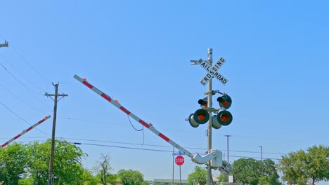 rail road crossing with red lights flashing and barriers coming down