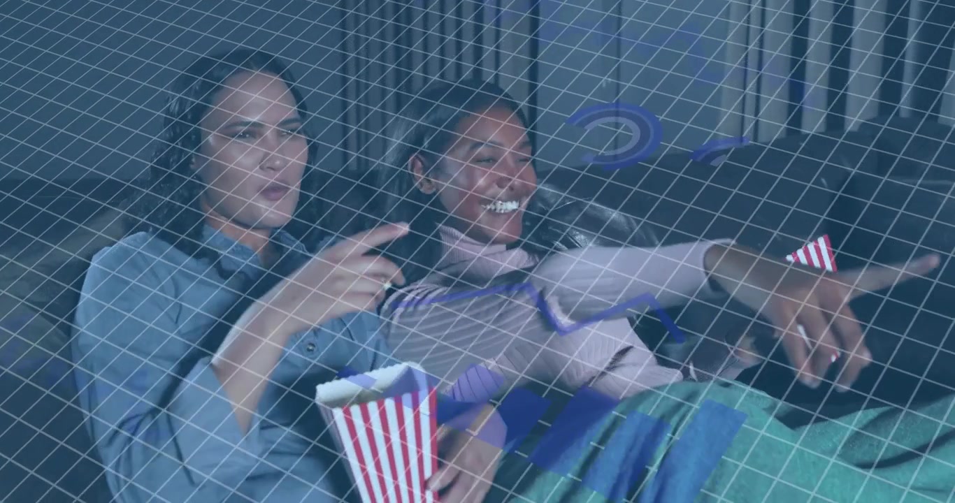 Due donne che condividono una coperta sul divano, prendono popcorn e ridono, con una sovrapposizione a griglia che migliora i contenuti multimediali.