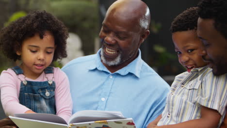 smiling multi-generation family reading book in garden together