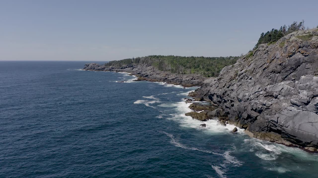 Drone flying around a coastal cliff on the rocky coastline off a small island in Maine