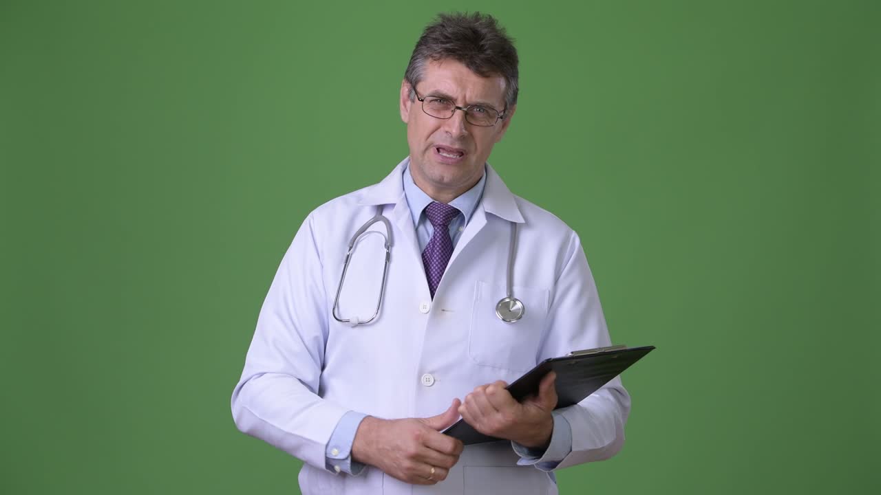 Medico uomo maturo e di bell'aspetto su sfondo verde.