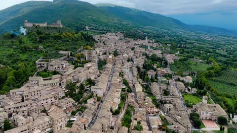 Vista-Aérea-De-La-Ciudad-De-Asís-Y-Comuna-Con-La-Fortaleza-De-Rocca-Maggiore-Durante-El-Día-En-Italia