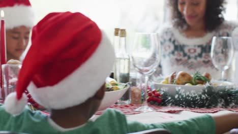 Feliz-Familia-Multigeneración-Afroamericana-Con-Gorros-De-Papá-Noel-Y-Celebrando-En-La-Cocina