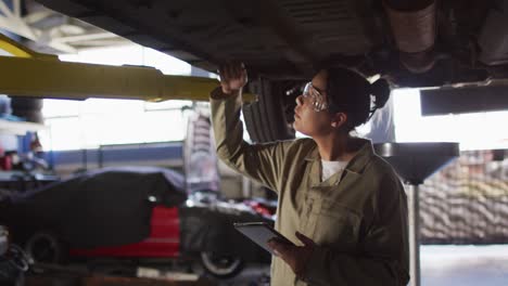 Video-of-biracial-female-car-mechanic-checking-car