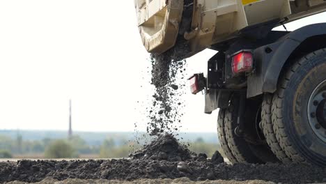 truck unloading gravel on a new road construction site, slow motion, close up